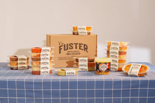 Caja de envío Ca Fuster con tarrinas de packs, sobre mantel de cuadros azules